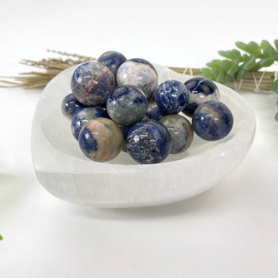 angled view of many sodalite sphere balls in a heart bowl for thickness