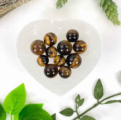 overhead view of many tigers eye spheres in a heart bowl for possible variations
