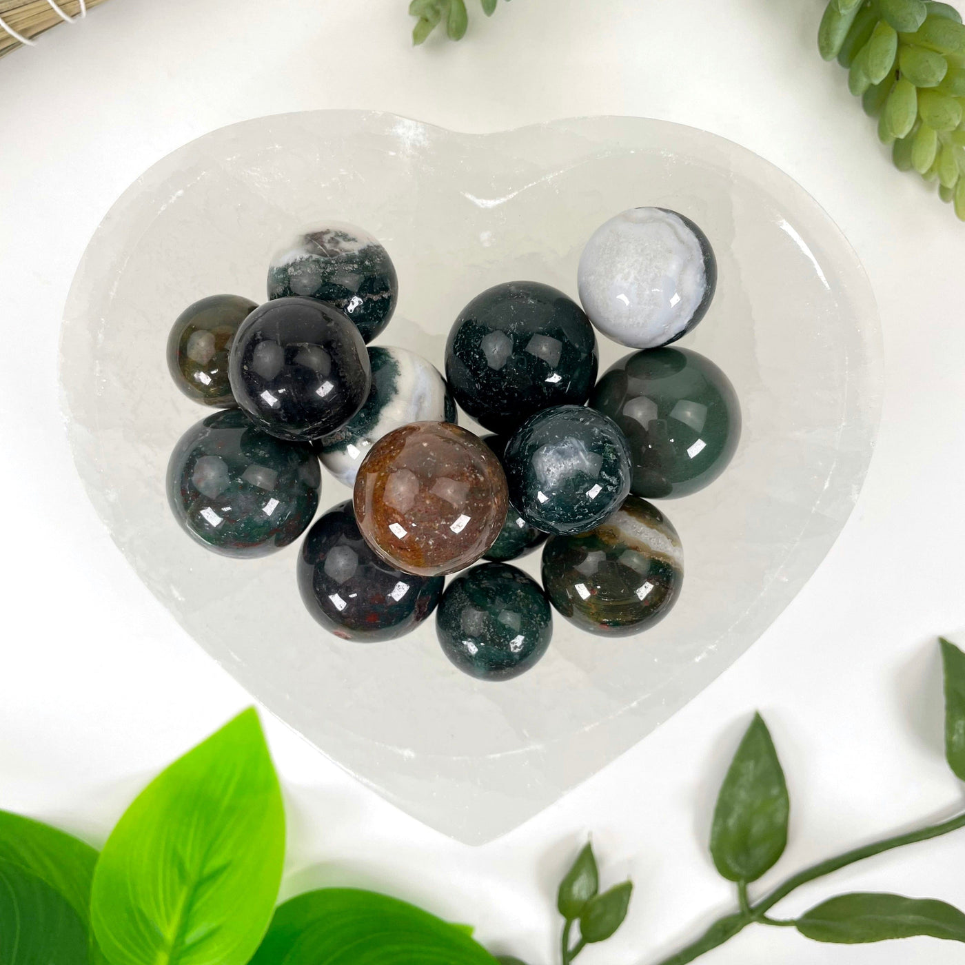 close up of many bloodstone agate spheres in a heart bowl for possible variations and details