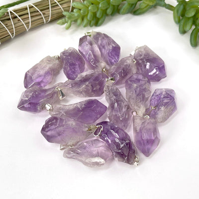 many tumbled amethyst pendants in a pile