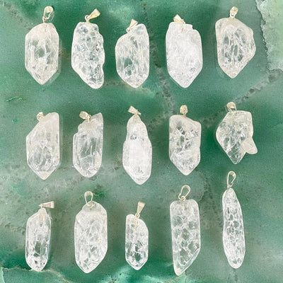 many crackle quartz point pendants in three rows on green background for possible variations