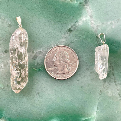 approximate largest and smallest crackle quartz point pendants on green background with quarter for size reference