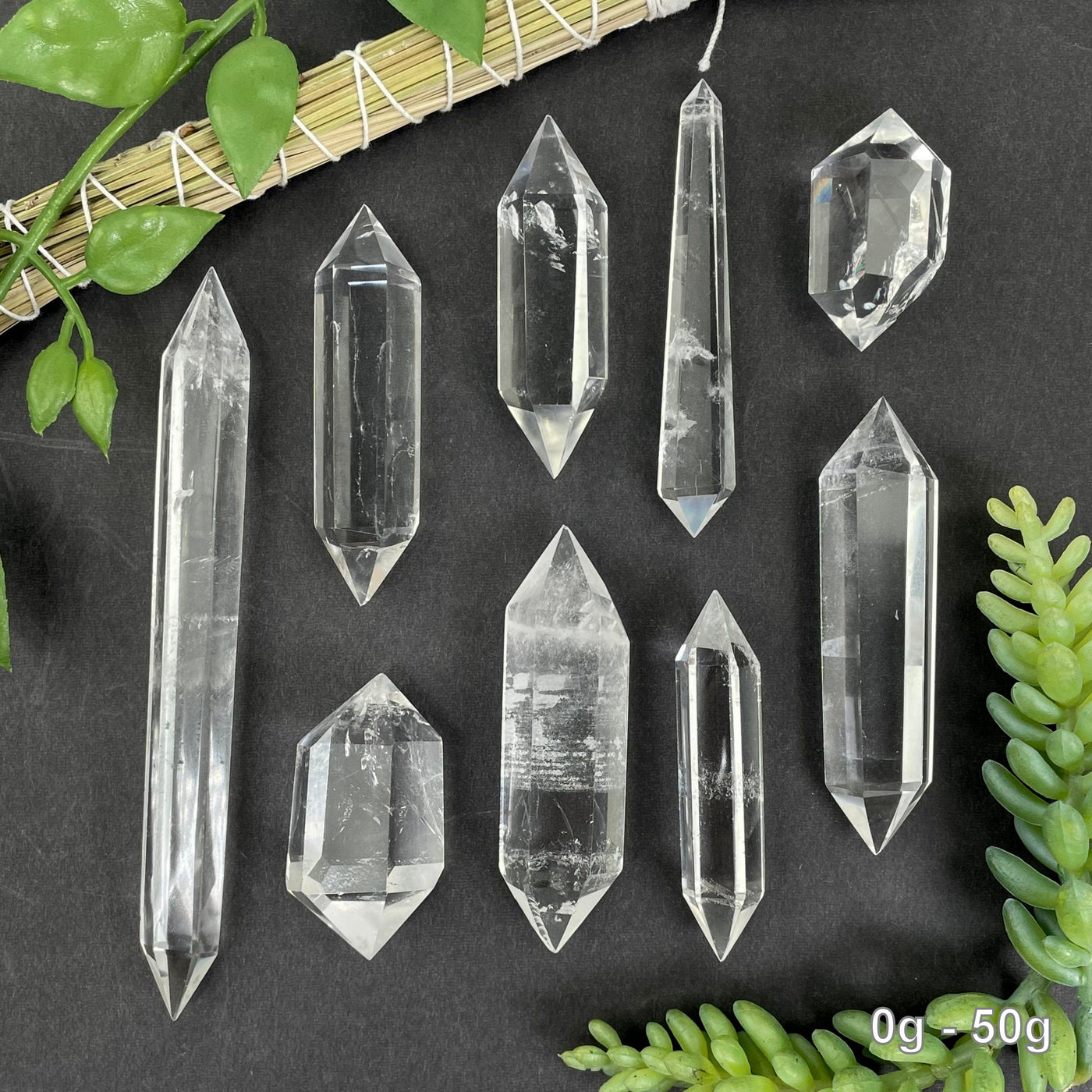 many 0g - 50g crystal quartz points on black background with plant decorations for possible variations