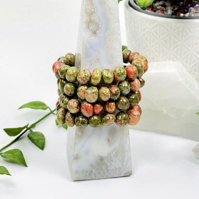 4 Unakite Multi-sized Bead Bracelets being held on a tower 