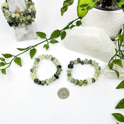 2 prehnite bracelets with a quarter for comparison with decorations in the background