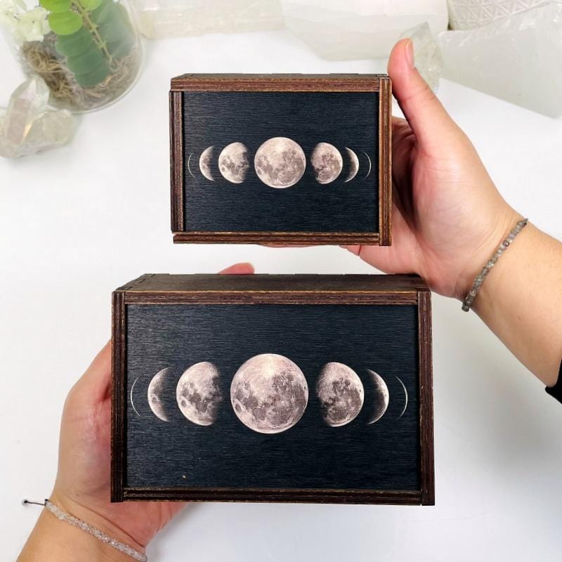 hands holding up 2 different sized Wooden Storage Box  with decorations in the background