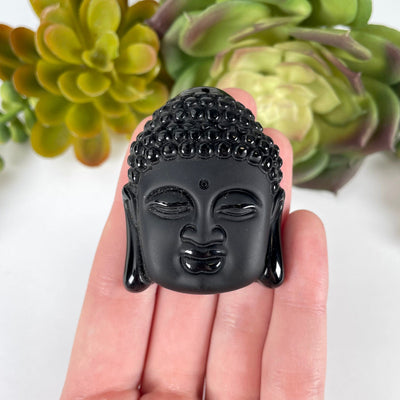 close up of one large black onyx buddha head bead in hand for size reference and details