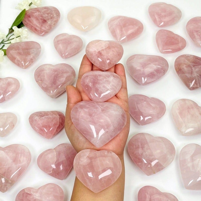 rose quartz hearts in hand with white background 