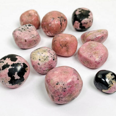 different sizes of tumbled rhodonite stones on white background 