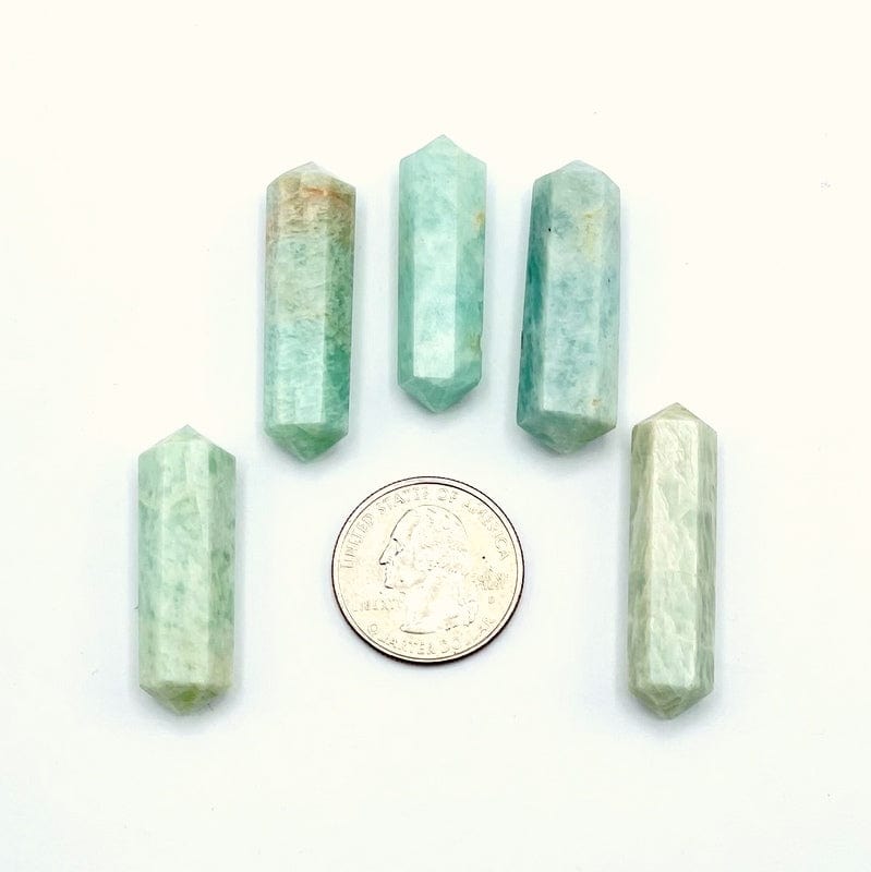amazonite double terminated points next to a quarter for size reference on a white background 