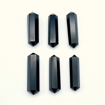 black obsidian double terminated pencil point gemstones on a white background