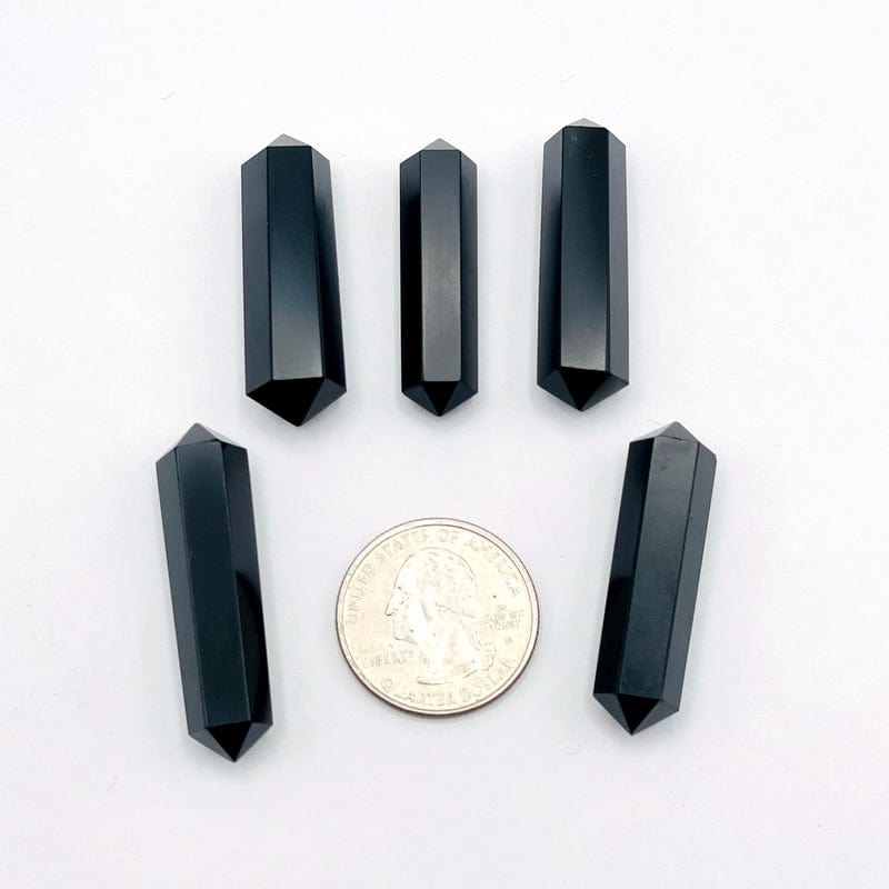 black obsidian double terminated pencil points next to a quarter for size reference. 