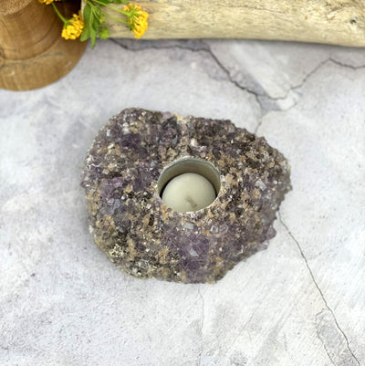 Amethyst cluster candle holder on a gray background.