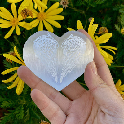 Selenite Stone Heart - Selenite Heart with Angel Wing Engraving upclose in a hand 
