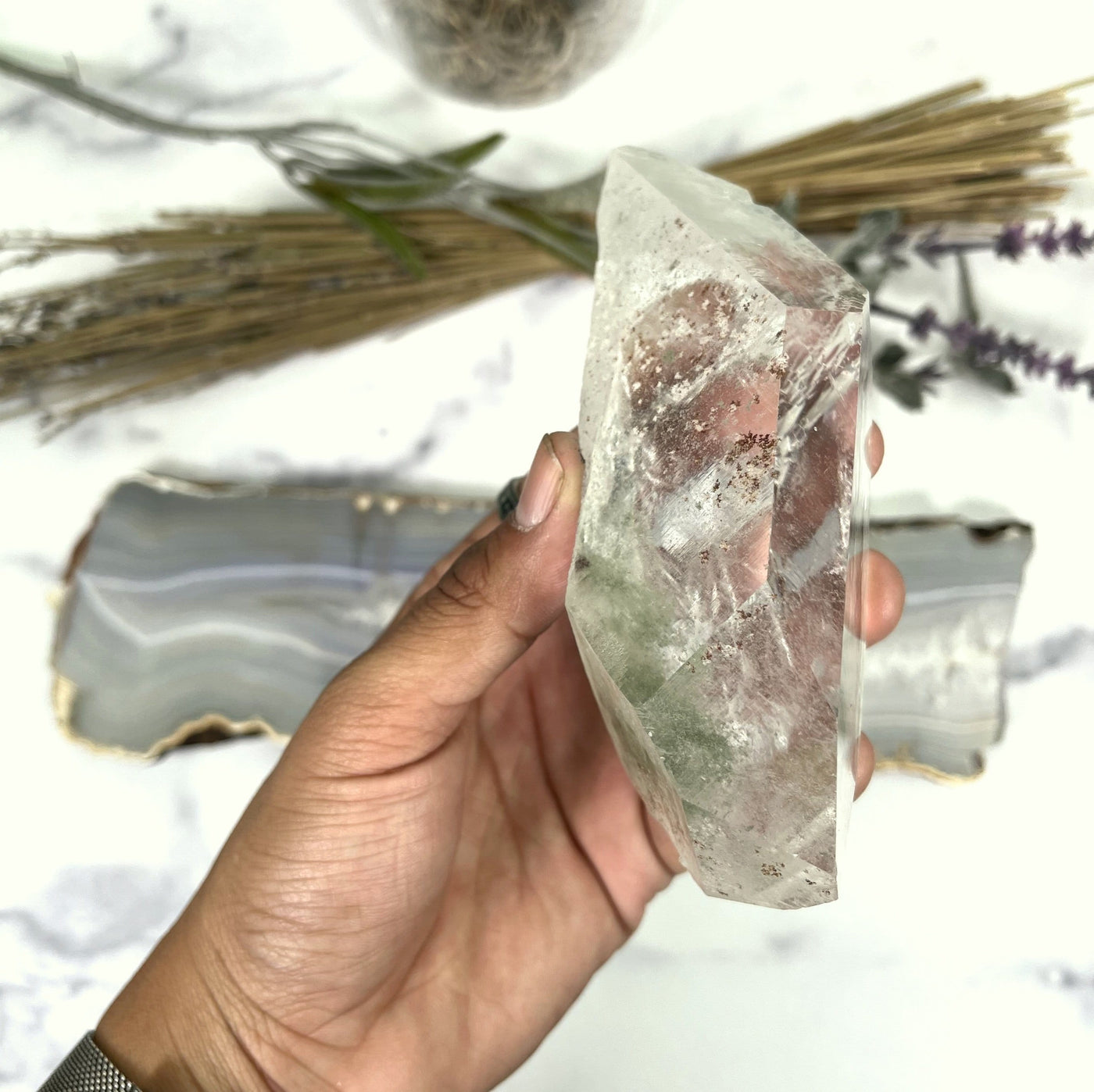 hand holding up Crystal Quartz with Chlorite with decorations in the background
