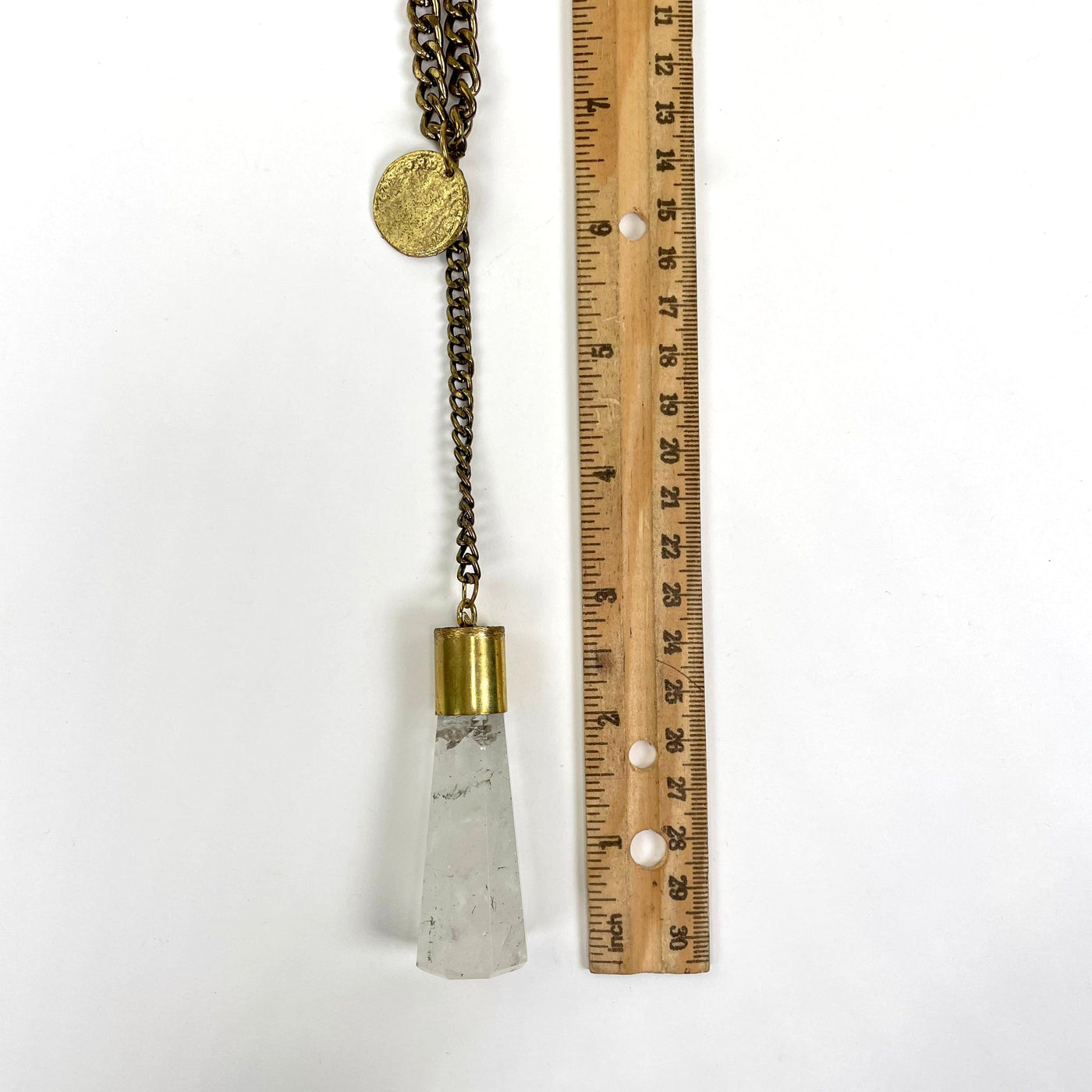 gold coin, pendant chain, and crystal quartz pendant on white background with ruler for size and length reference