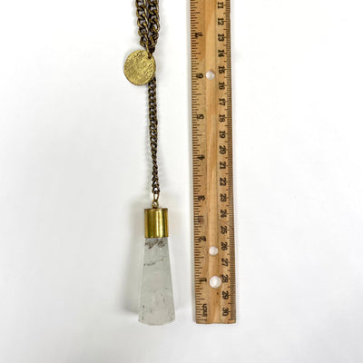 gold coin, pendant chain, and crystal quartz pendant on white background with ruler for size and length reference