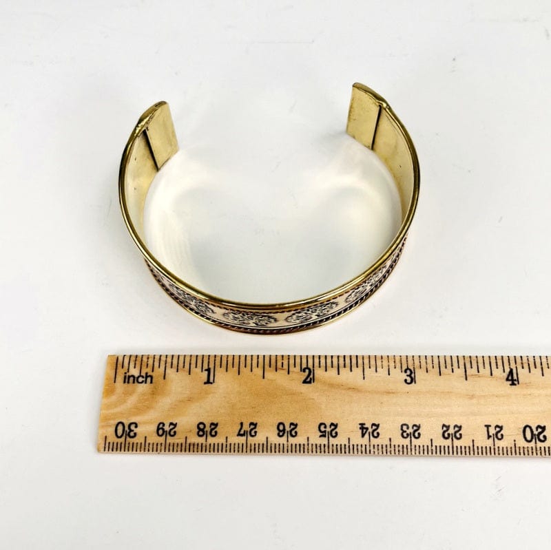 brass bracelet next to a ruler for size reference 