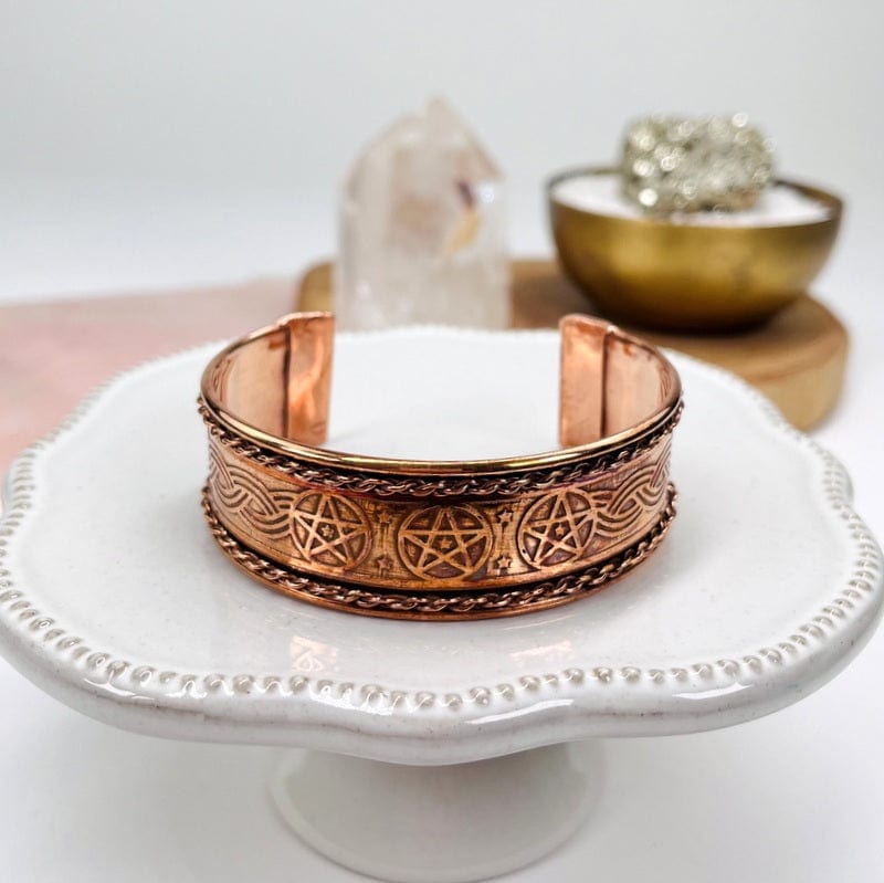 copper cuff bracelet with stars and chain accent displayed as decor 