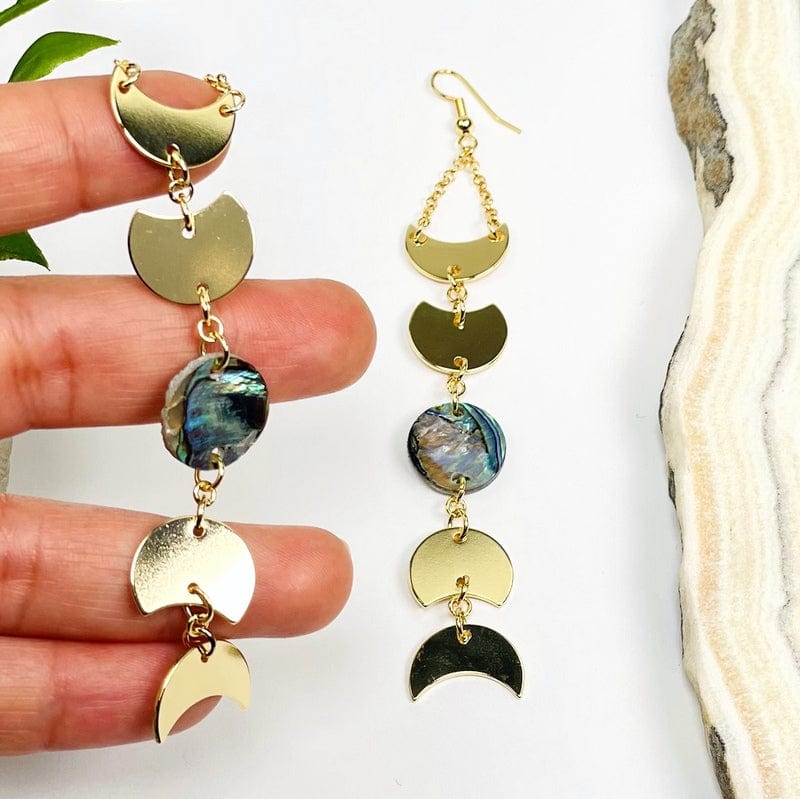 gold moon phase earrings with a abalone center accent in hand for size reference 