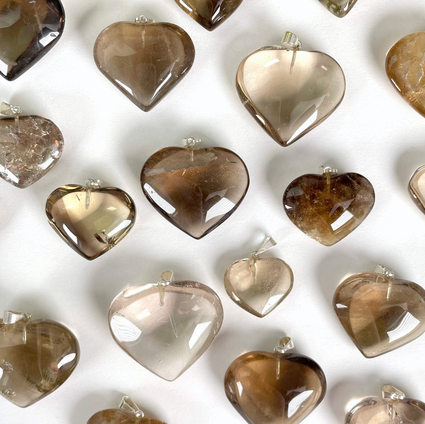 overhead view of many natural citrine heart pendants on white background for possible variations