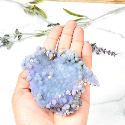 hand holding up Grape Agate Cluster with decorations in the background