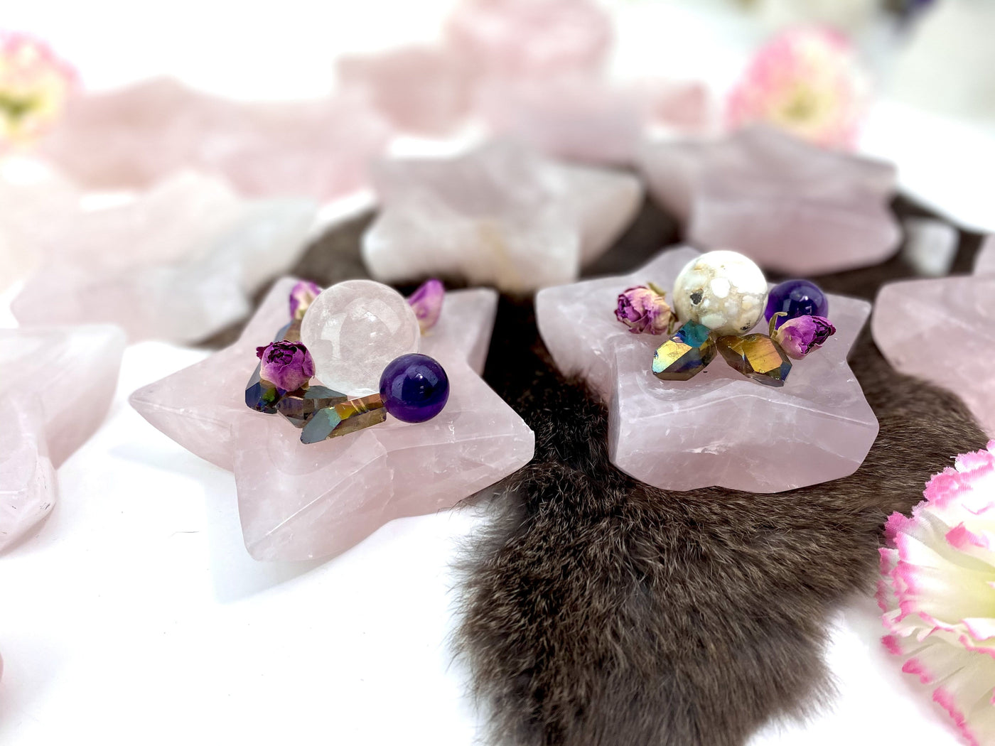 2 Rose Quartz Stone Star Dishes filled with crystals with others blurred in the background