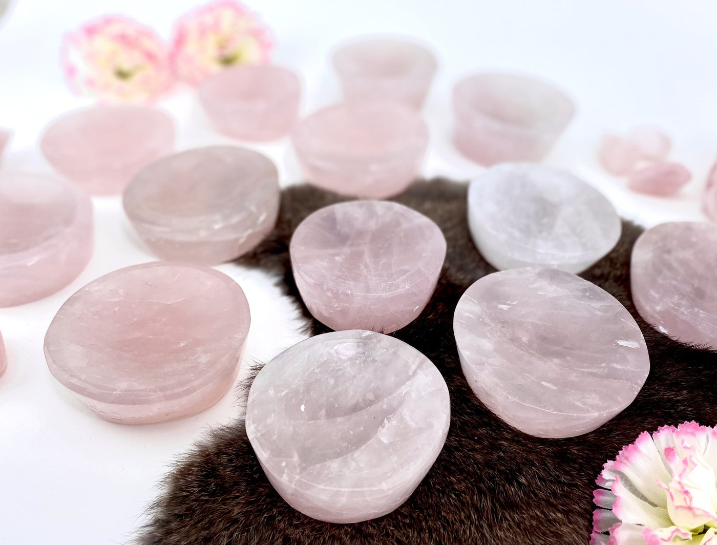 Angled shot of Rose Quartz Stone Round Dishes with fur and flower decorations