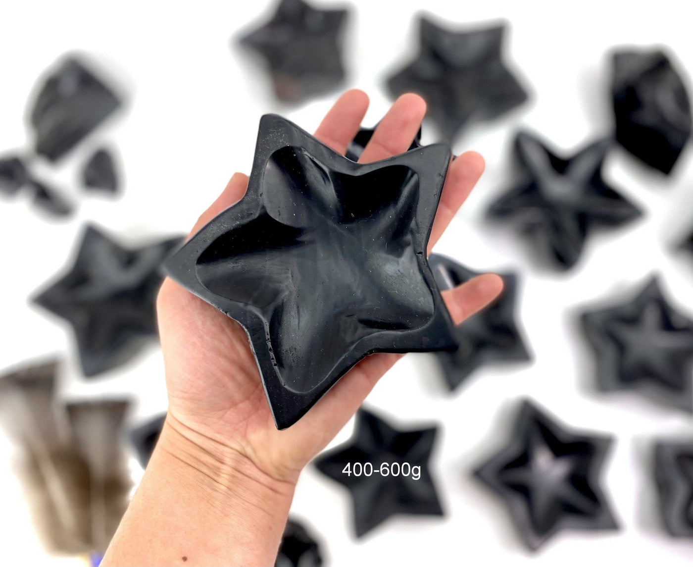 Black Obsidian Stone Star Dish in a hand sowing size 400-600g size, with others in the backbround