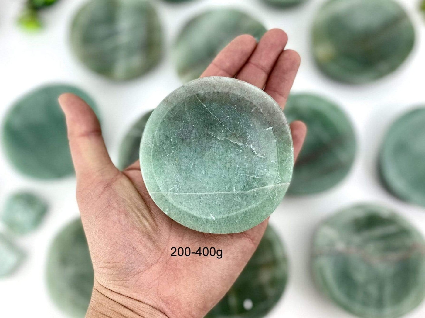 hand holding up Green Aventurine Stone Round Dish with others in the background