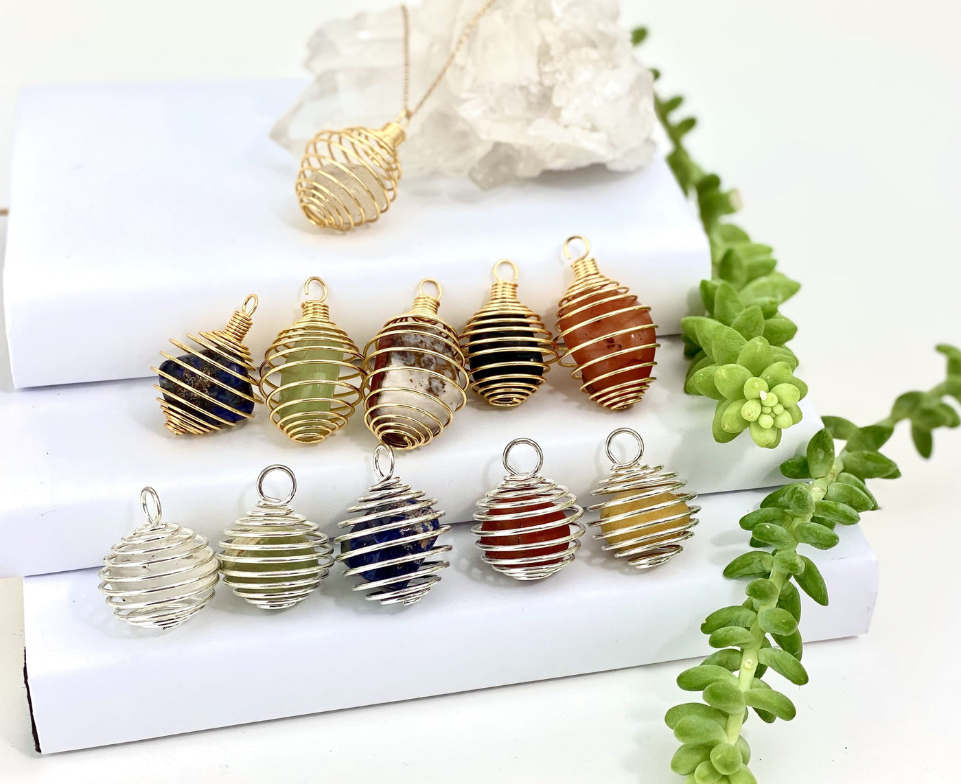 tumbled stone cage pendants in gold and silver with decorations in the background