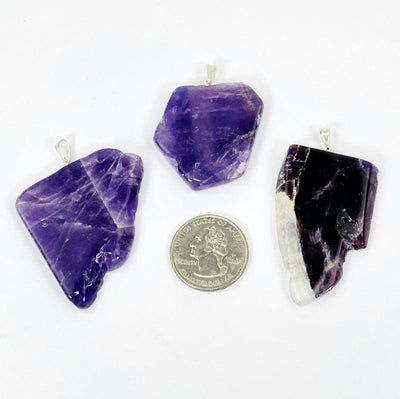 amethyst slab pendants with silver bail next to a quarter for size reference 