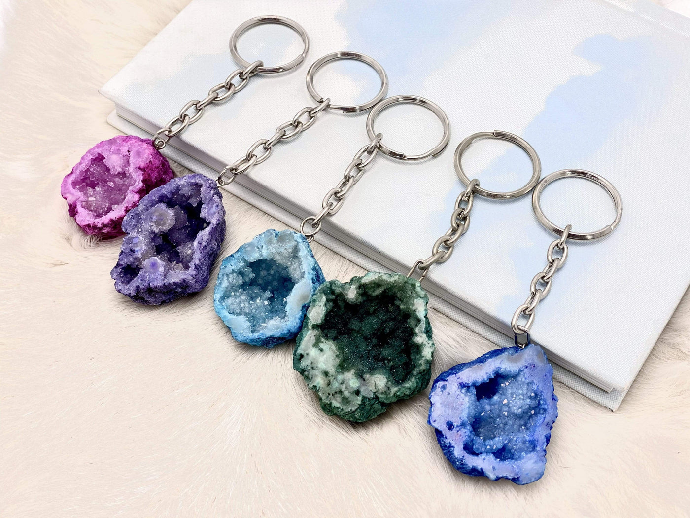different colored half occo geode silver toned keychain shown against a white background showing the shiny crystals inside