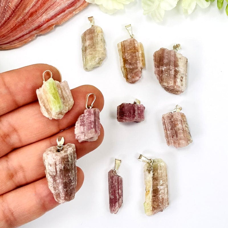 pink/green tourmaline pendants displayed on hand for size reference