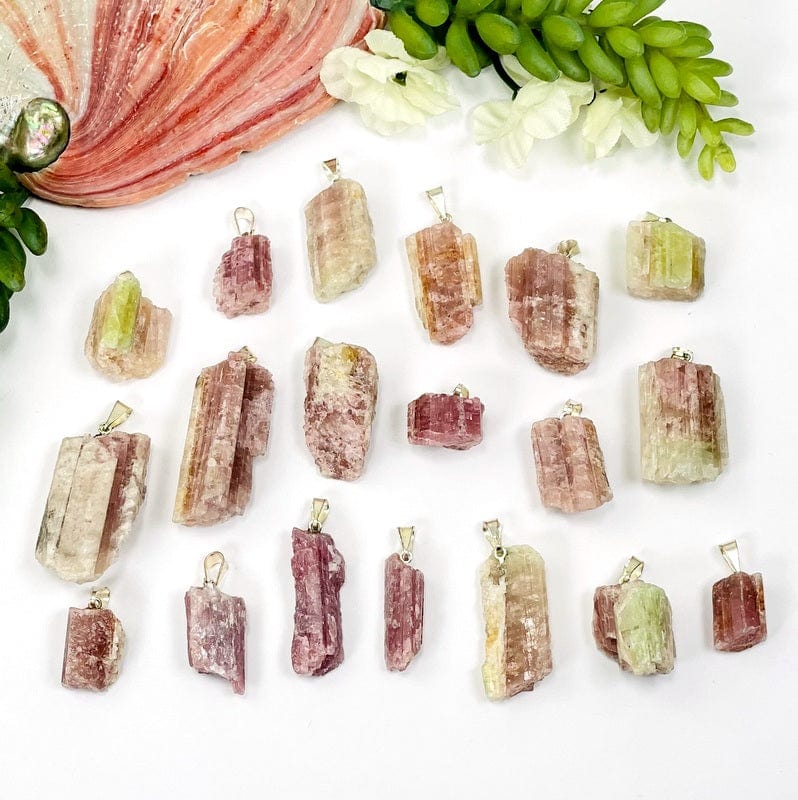 pink/green tourmaline pendants with silver toned bail on white background showing different sizes and textures 