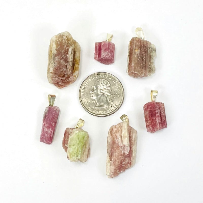 pink/green tourmaline pendants with silver toned bail next to a quarter for size reference 