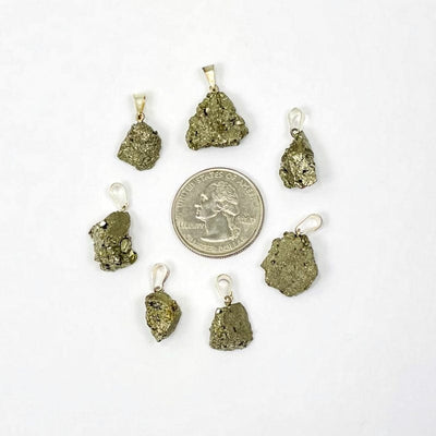 pyrite pendant with silver bail next to a quarter for size reference 