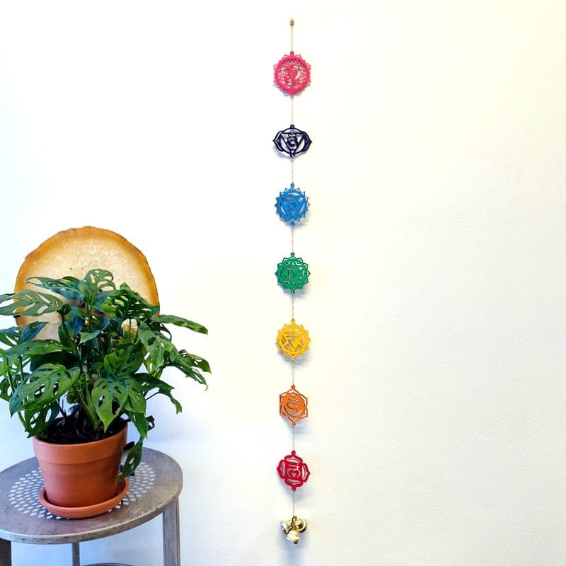 colorful wooden wall hanger with seven chakra symbols and three bells accent on the bottom 