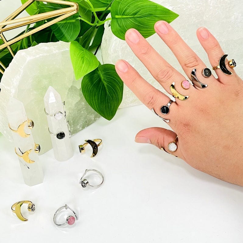 multiple moon rings with gemstone accents in gold and silver on hand 