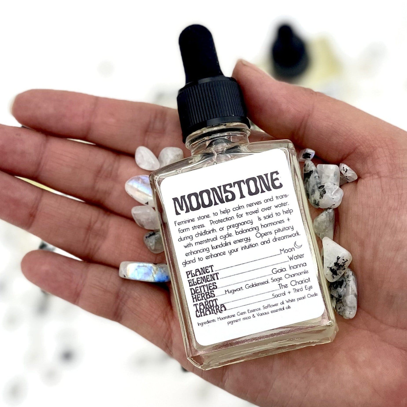 hand holding up Moonstone Gem Essence with moonstone chips
