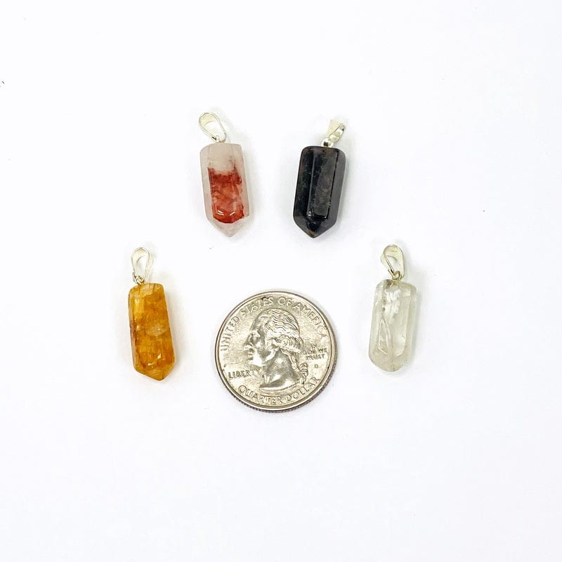 gemstone point pendant with silver toned bail next to a quarter for size reference 