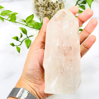 hand holding up Crystal Quartz Point with decorations in the background