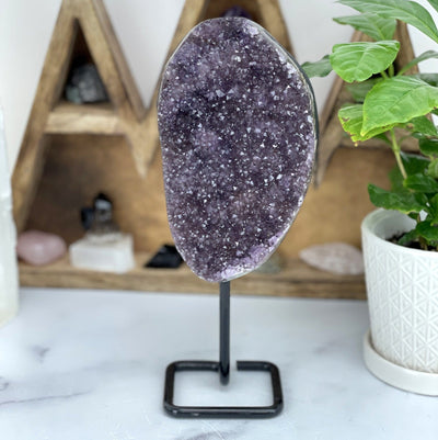 Amethyst cluster on a black metal stand.