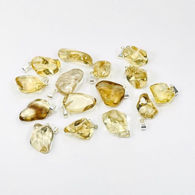 Natural Citrine Tumbled Stone with a Silver Bail - scattered on a table