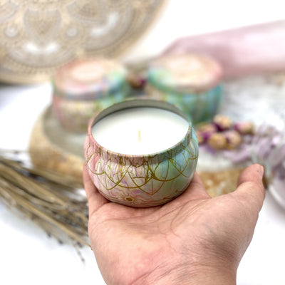 hand holding up Gratitude Candle Tin with decorations blurred in the background