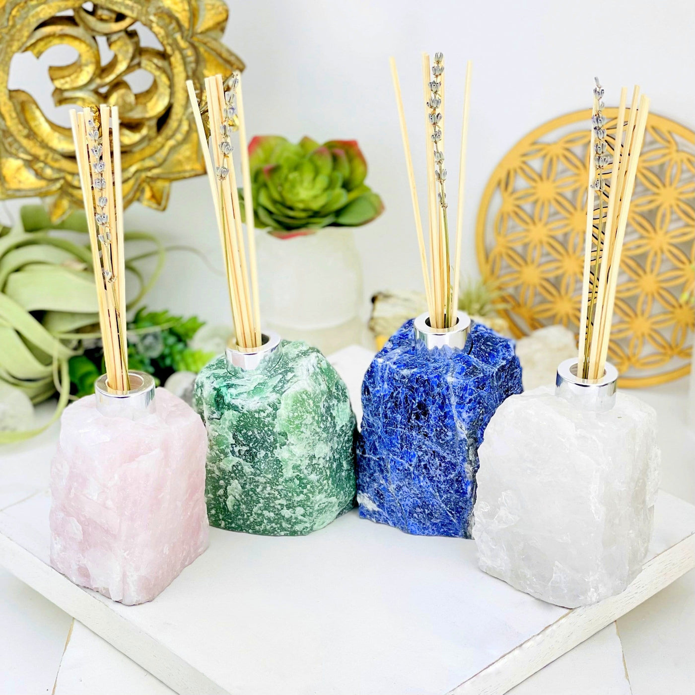 4 diffuser bottles of different crystals with decorations in the background