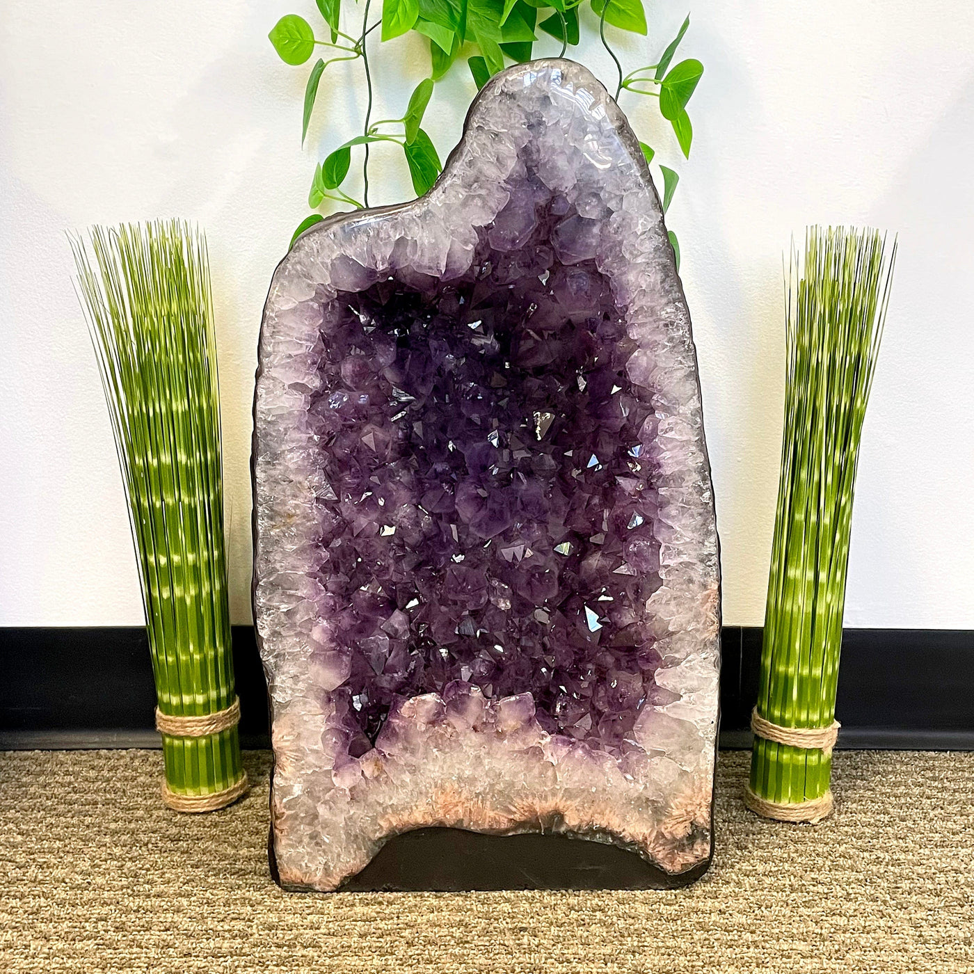 front of amethyst cave geode on display in front of plant décor 