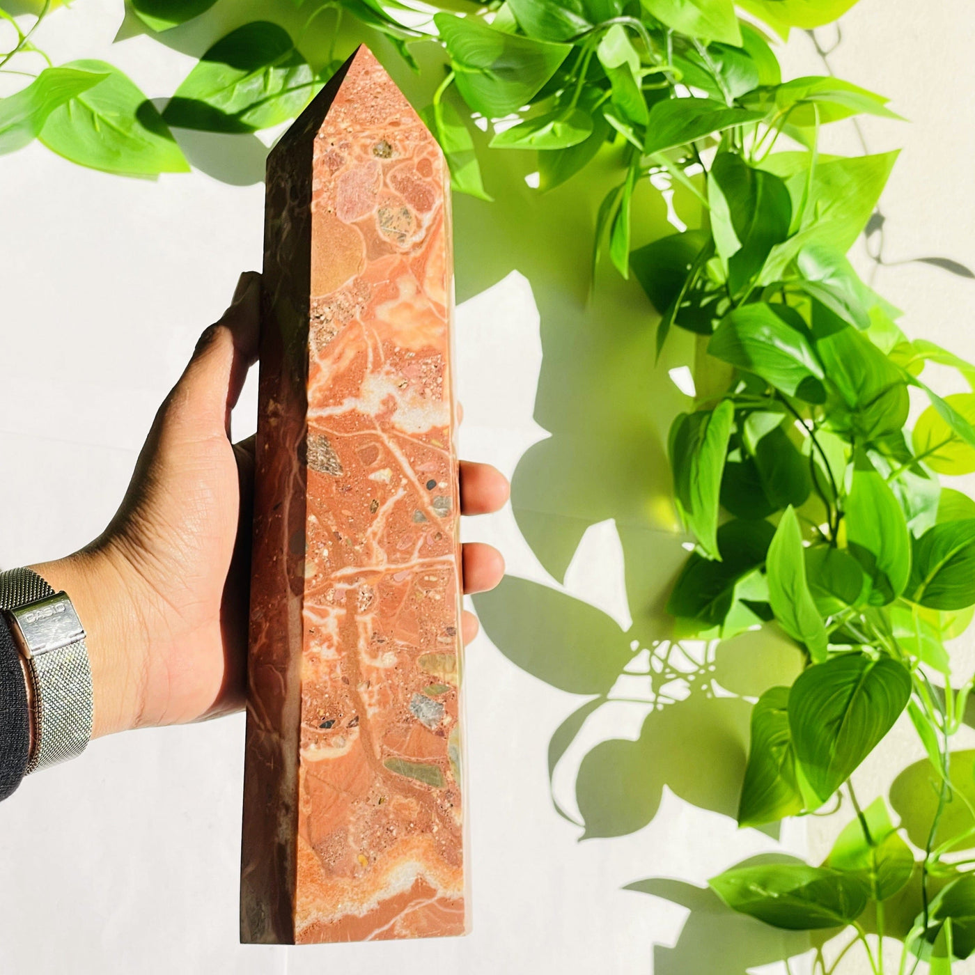 hand holding Red jasper tower with floral background