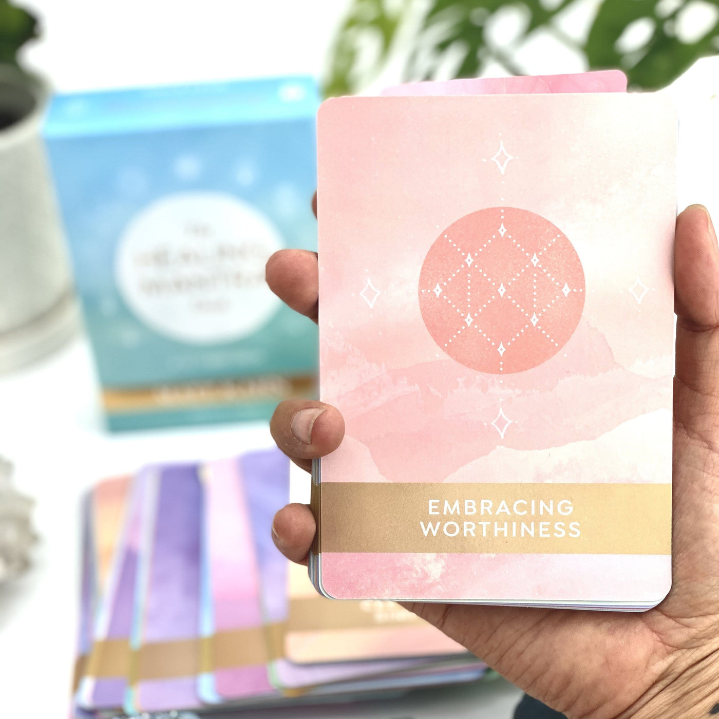 Hand holding one of the cards Embracing worthiness in a pink color 