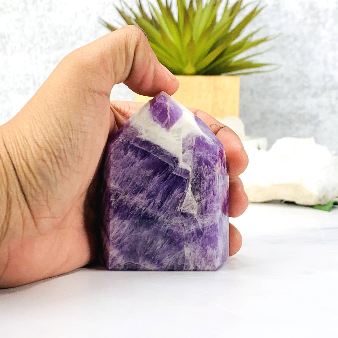 Hand comparing size to the  Chevron Amethyst Polished Point